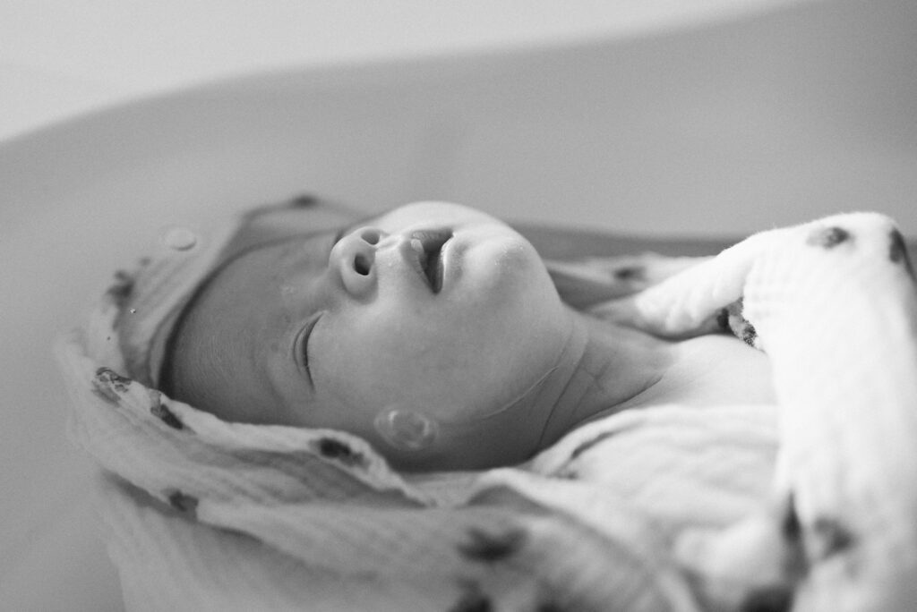 nouveau né photographié par Marie Cavelier dans son thérapeutique bain bébé photographie pour un cadeau de naissance original